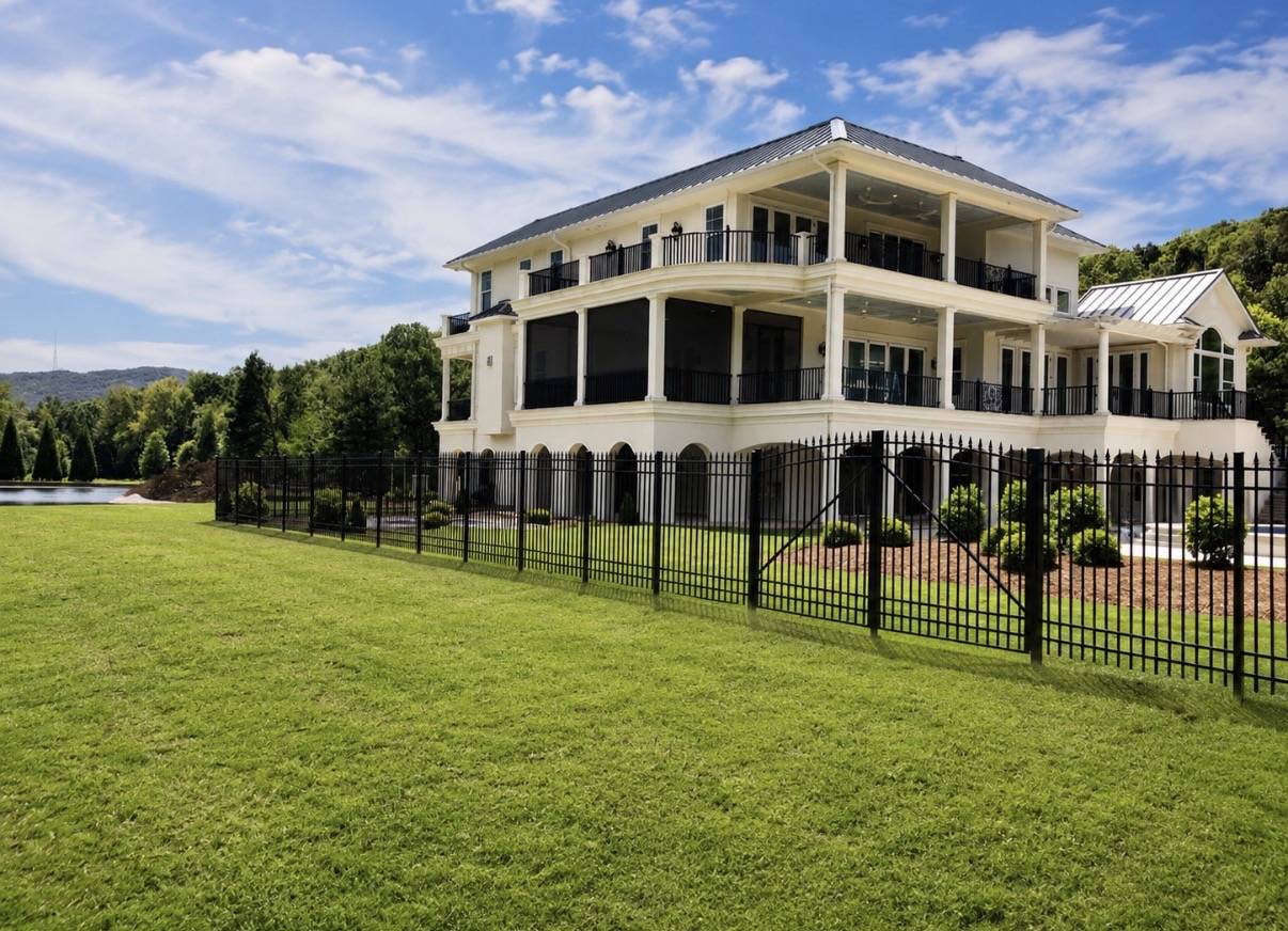 Black aluminum fence in front of large home
